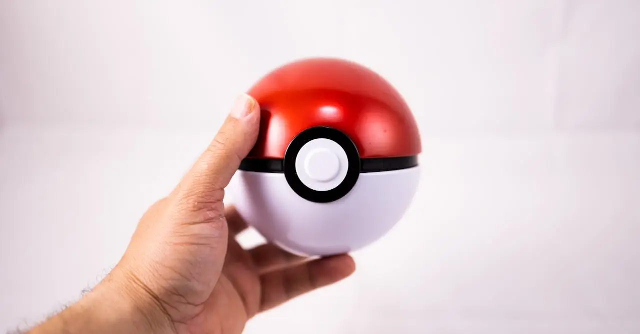 Crafting Captivating Headlines: Your awesome post title goes here Close-up of a human hand holding a red Pokeball toy against a white background.